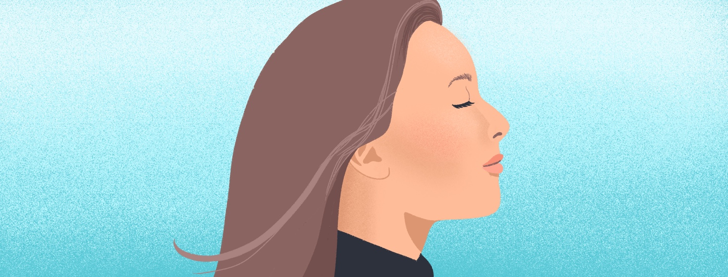 A woman stands happily in a breeze against a blue sky