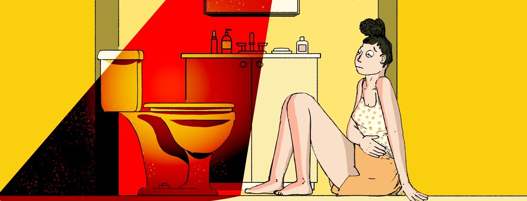 A woman sits uncomfortably on the bathroom floor with her hand over her stomach and staring warily at the toilet in front of her which is illuminated by an evil red light